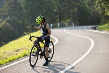 Woman cyclist using mobile phone at summer park