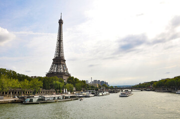 The Seine River in Paris with a historic bridge and the illuminated Eiffel Tower in the background. The calm water reflects the city lights, creating a romantic atmosphere of a Parisian evening