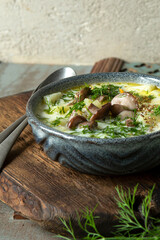 ceramic bowl with soup of young potatoes with butter mushrooms on the table
