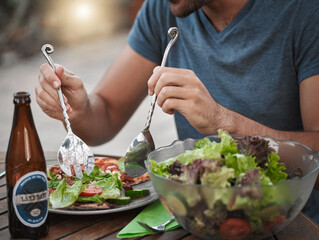 Cutlery, hands and salad with person outdoor in backyard of home for break, drinking or eating. Beer, food and meal with healthy vegetable snack on wooden table for cuisine, diet or organic nutrition