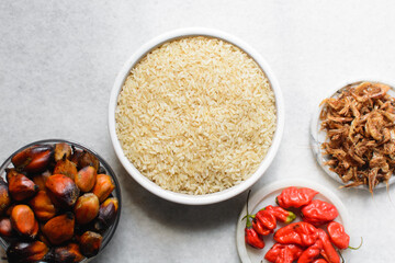 mise en place of ingredients of nigerian banga rice, process of making palm nut rice, top view of rice, palm nut,crayfish and pepper on a table