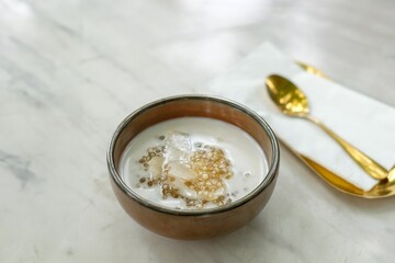 A Bowl of Oatmeal with Banana Slices and a Gold Spoon on a Marble Table, Representing a Healthy Breakfast.