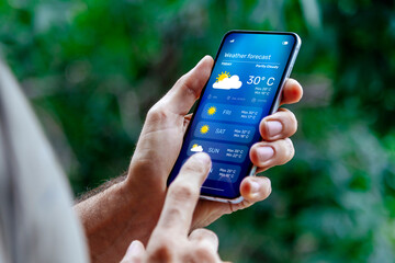 Man outdoors checking weather forecast on his mobile phone.