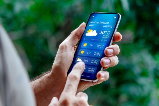 Man outdoors checking weather forecast on his mobile phone. - Powered by Adobe