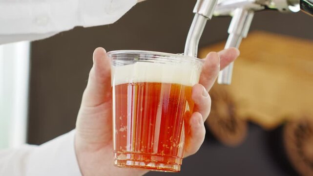 The bartender pours beer into plastic cups. holiday service.