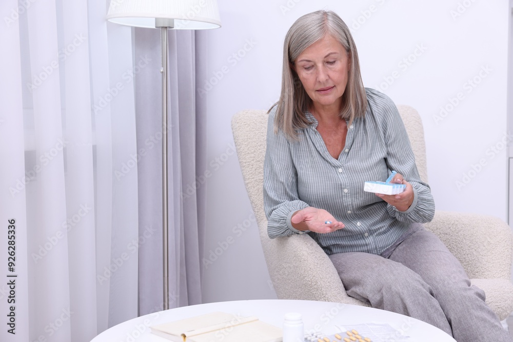 Canvas Prints Senior woman with pills and organizer in armchair at home