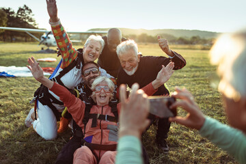 Group of senior skydivers taking a selfie after landing