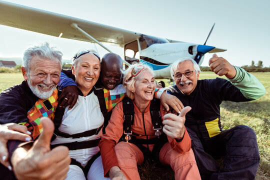 Diverse senior people taking group selfie before skydiving