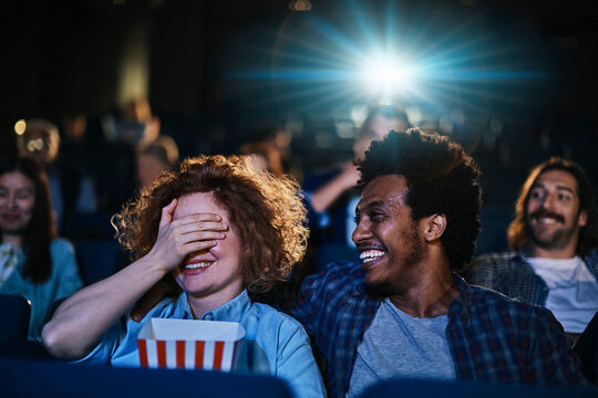 Smiling young couple watching a movie in cinema