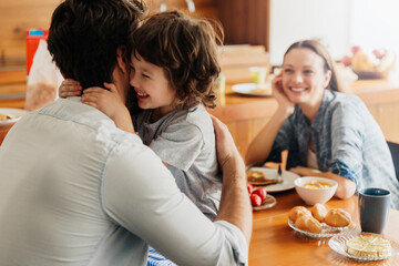 Happy family breakfast with father and son hugging
