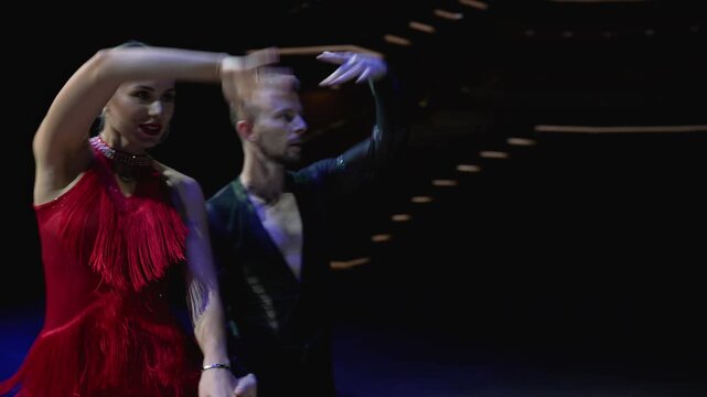 Feet closeup of Argentinian tango dancer in a red dress. Ballroom couple dancing on stage.