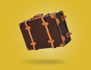 Vintage suitcase in air on yellow background