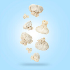 Delicious khinkali (Georgian dumplings) falling on light blue gradient background
