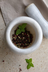 Peppercorns and fresh basil in a mortar
