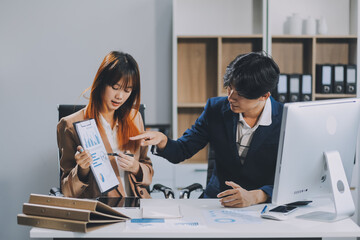 Entrepreneur Asian businessman and businesswoman discussing new business project in tablet in modern Meeting In Modern Office, Asian business casual concept.