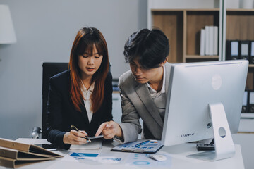 Entrepreneur Asian businessman and businesswoman discussing new business project in tablet in modern Meeting In Modern Office, Asian business casual concept.