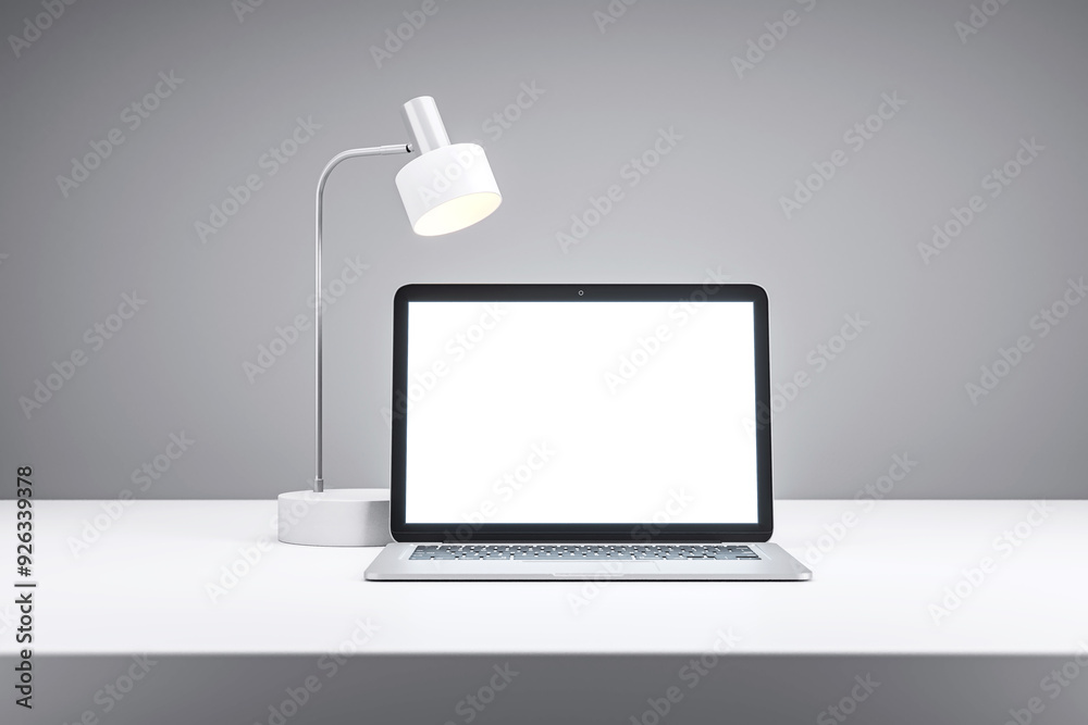 Poster laptop with blank screen and desk lamp on white table in grey room. 3d rendering