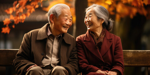 Obraz premium Japanese senior couple is enjoying each other's company in a peaceful moment surrounded by the beautiful colors of a japanese garden in fall. Keiro no hi, or respect for the aged day. Banner.