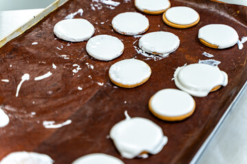 Cookies with white icing on a baking sheet. Biscuit production. Mini bakery or industrial production line for flour products. High quality photo