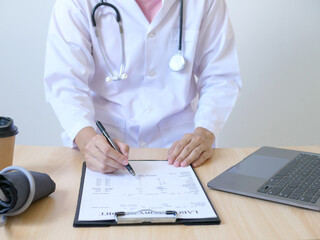 Young Asian female doctor sitting and diagnosing test results of a patient in hospital