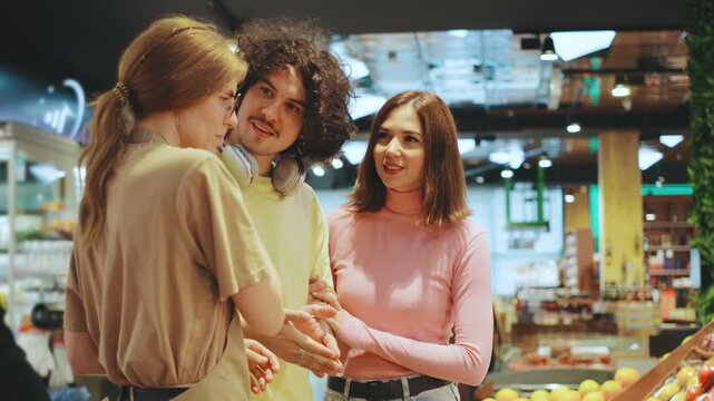 A couple is in a grocery store, discussing with a female salesperson in the produce section. She is giving helpful tips on choosing fresh fruits and vegetables.