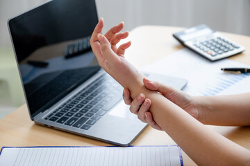 A successful business woman sitting in the office Using a laptop to work so hard that it hurts her wrists