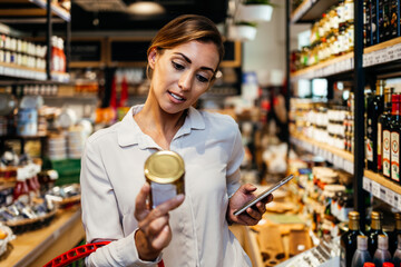Beautiful young and elegant woman buying some healthy food and drink in modern supermarket or grocery store. Lifestyle and consumerism concept.