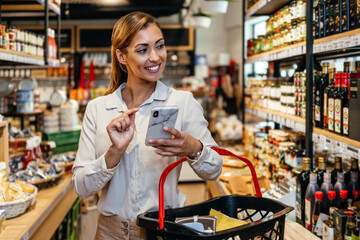 Beautiful young and elegant woman buying some healthy food and drink in modern supermarket or grocery store. Lifestyle and consumerism concept.
