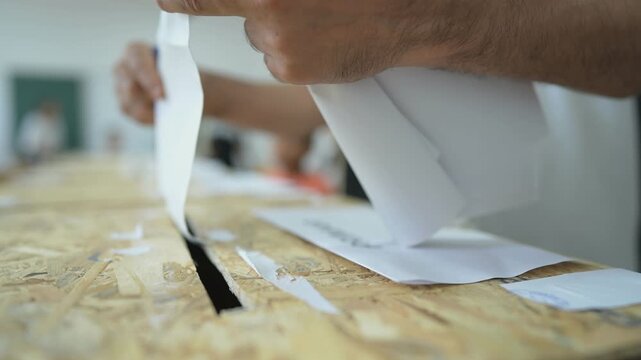 A person inserts a ballot in a box while voting at a polling station during elections.