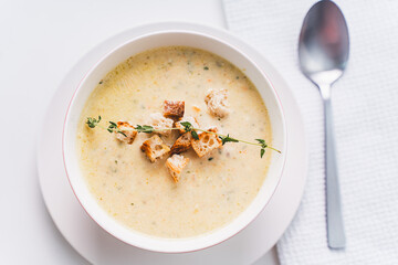 Cream soup with croutons and thyme in a white plate on the table. Selected focus. High quality photo