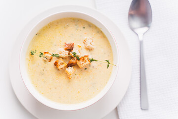 Cream soup with croutons and thyme in a white plate on the table. Selected focus. High quality photo