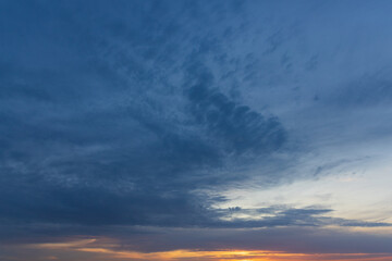 Dark blue sunset sky with cloud and yellow-orange stripe of sun