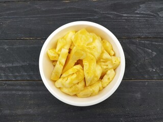 Pineapple pieces in bowl on the wooden table 