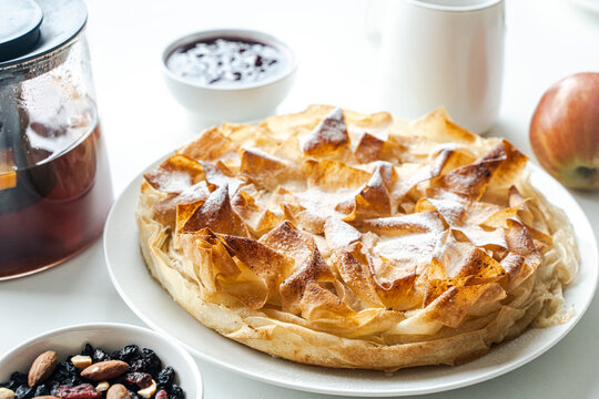 Homemade pastries, apple pie made of filet dough, nuts and tea on a white table. Selected focus. High quality photo