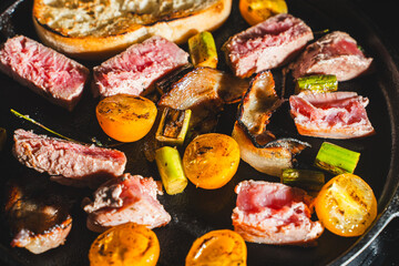 Tuna is seared in a cast-iron skillet with cherry tomatoes, asparagus, bacon and bread toast. High quality photo