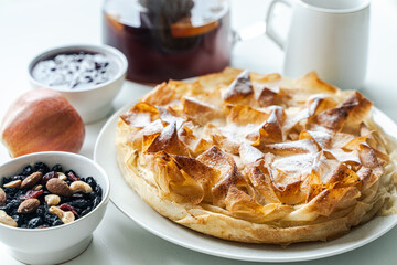 Homemade pastries, apple pie made of filet dough, nuts and tea on a white table. Selected focus. High quality photo