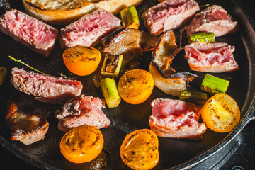 Tuna is seared in a cast-iron skillet with cherry tomatoes, asparagus, bacon and bread toast. High quality photo