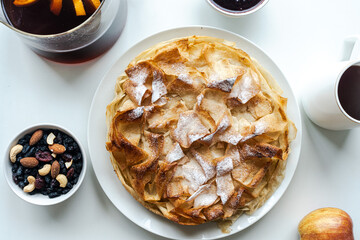 Homemade pastries, apple pie made of filet dough, nuts and tea on a white table. Selected focus. High quality photo