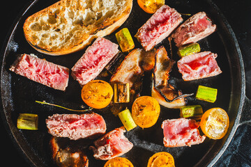 Tuna is seared in a cast-iron skillet with cherry tomatoes, asparagus, bacon and bread toast. High quality photo