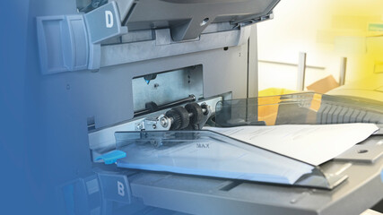 An enveloping machine at the letter shop prepares and processes letters and mailings for the post...