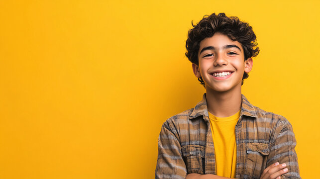 A joyful Latino Hispanic teen boy with a big smile on a vibrant yellow background.