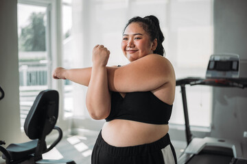 Plus size Asian woman exercises in gym. Beautiful overweight woman in sportswear smiling and happy in fitness. concept of body positive, self-acceptance, weight loss. - Powered by Adobe