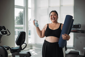 Plus size Asian woman exercises in gym. Beautiful overweight woman in sportswear smiling and happy in fitness. concept of body positive, self-acceptance, weight loss.