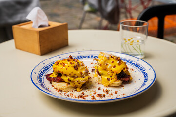 Delicious breakfast of poached eggs with bacon and potato pancakes with cheese sauce, street food.