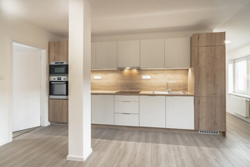 Bright, modern kitchen with wooden cabinets, sleek countertops, and integrated appliances. The space is well-lit with natural light and LED strips, creating a cozy and contemporary atmosphere.