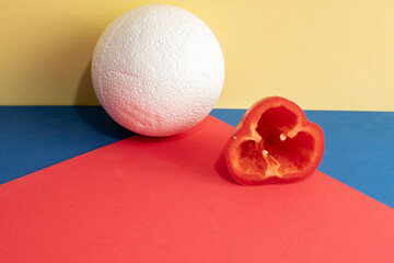Still life with a slice of a sweet bell pepper and plastic foam ball