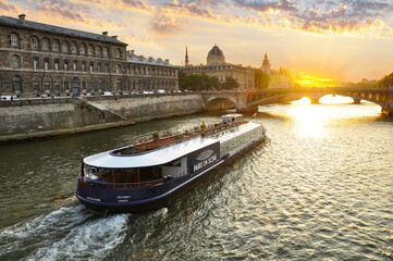 The Seine River in Paris with a historic bridge and the illuminated Eiffel Tower in the background. The calm water reflects the city lights, creating a romantic atmosphere of a Parisian evening