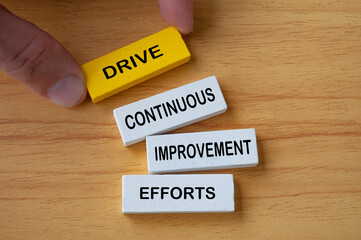 Top view of hand holding wooden blocks with text Drive Continuous Improvement Efforts. Process...