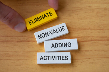 Top view of hand holding wooden blocks with text Eliminate non-value added activities. Process...