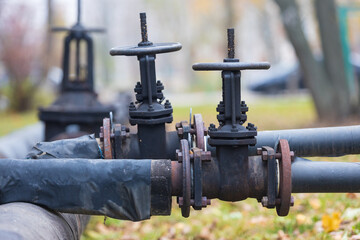 Close-up of shut-off valves on street main heating pipes. Huge industrial black valves on heating pipeline. Heating season in Russia background